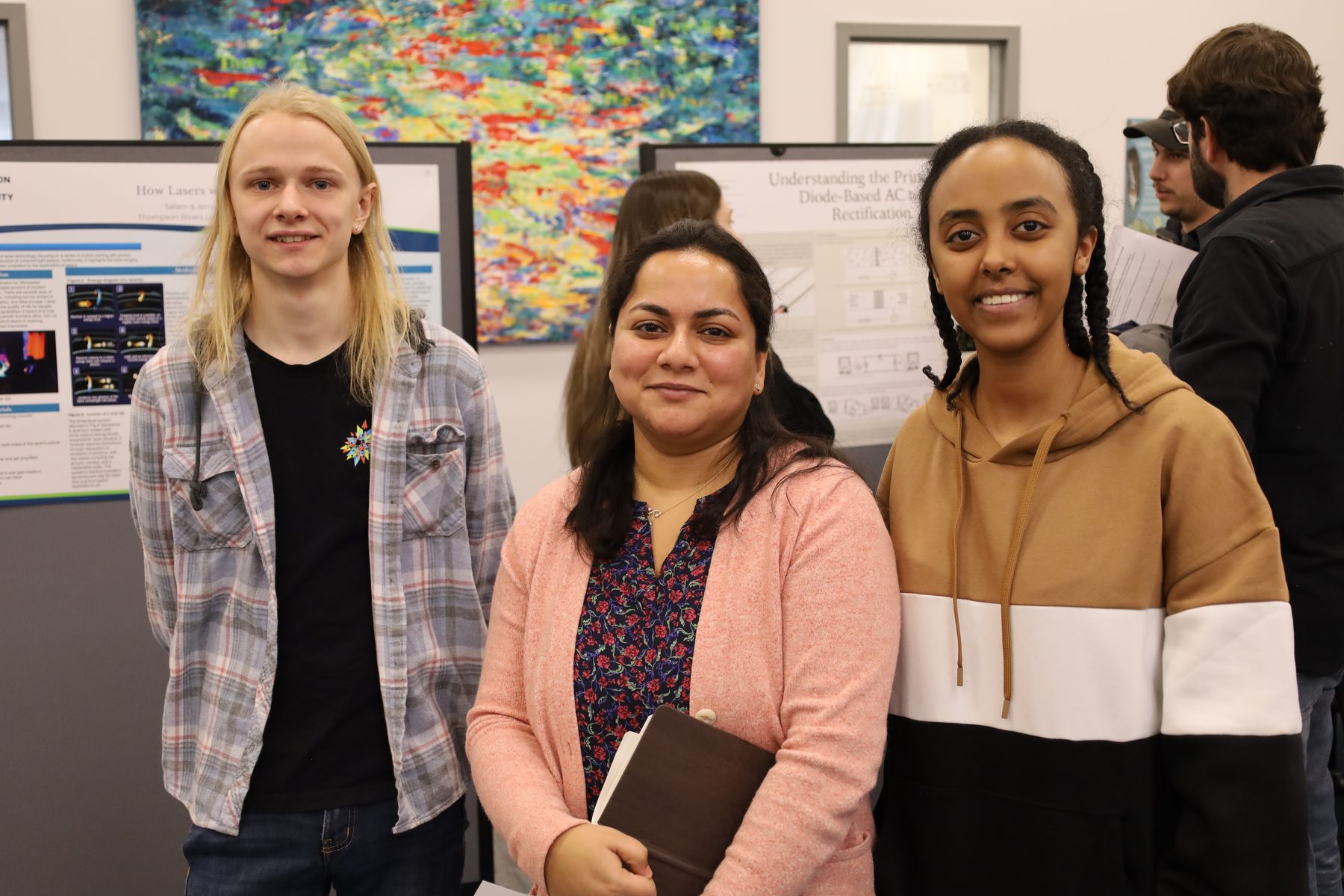 A faculty mentor stands with two students in front of their research posters.