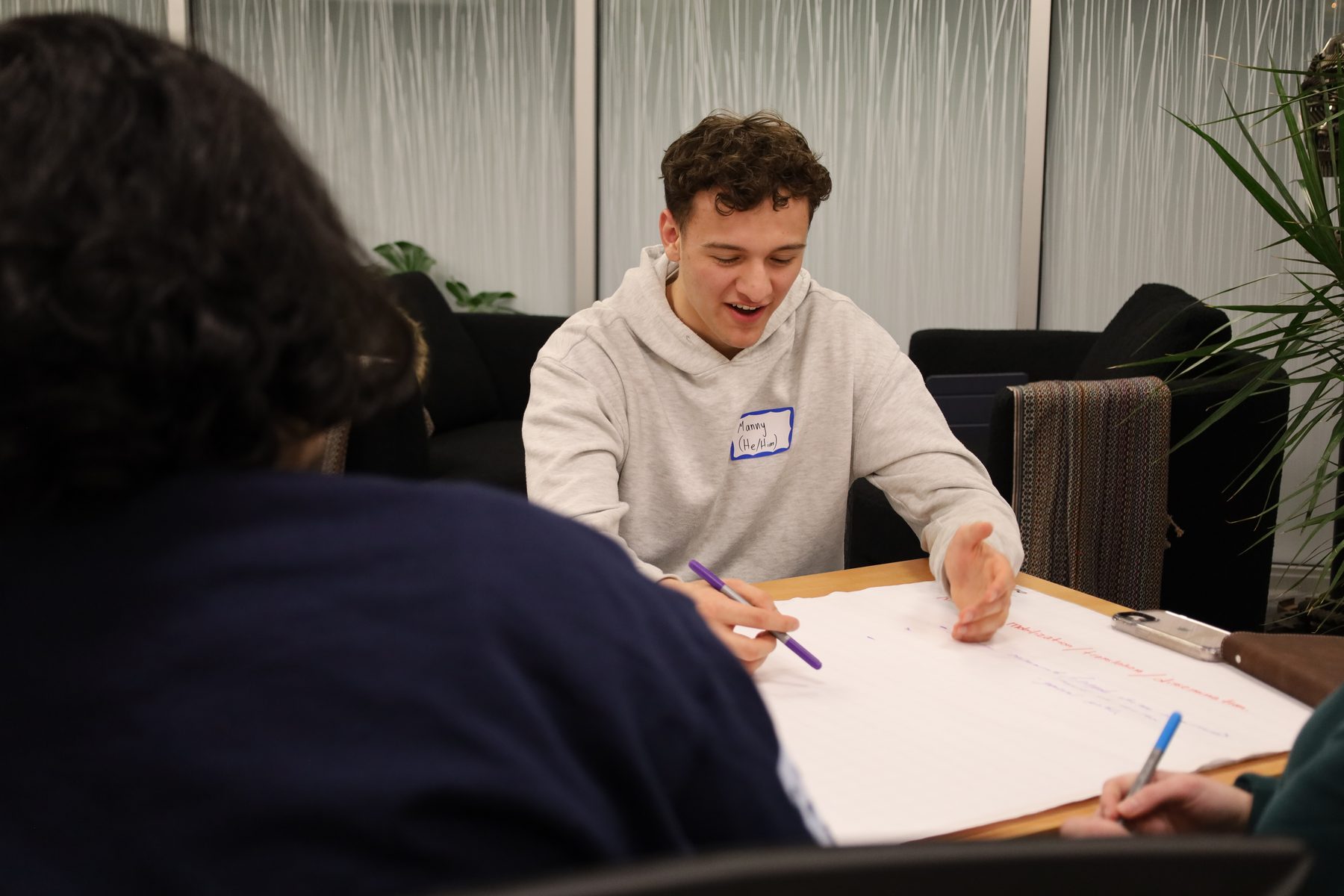 A student sketches ideas on a large sheet of paper during a one-on-one working session.