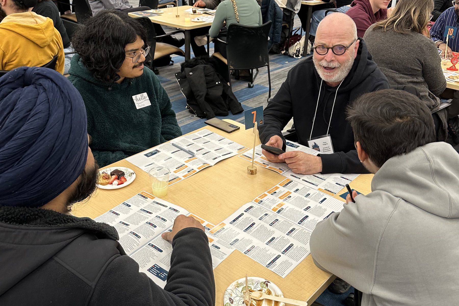 A faculty member meets with students at a table, talking through their research interests.